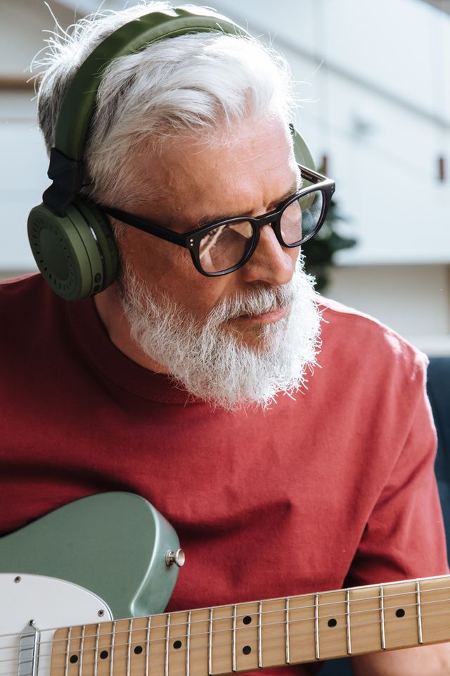 senior man playing guitar and wearing headphones